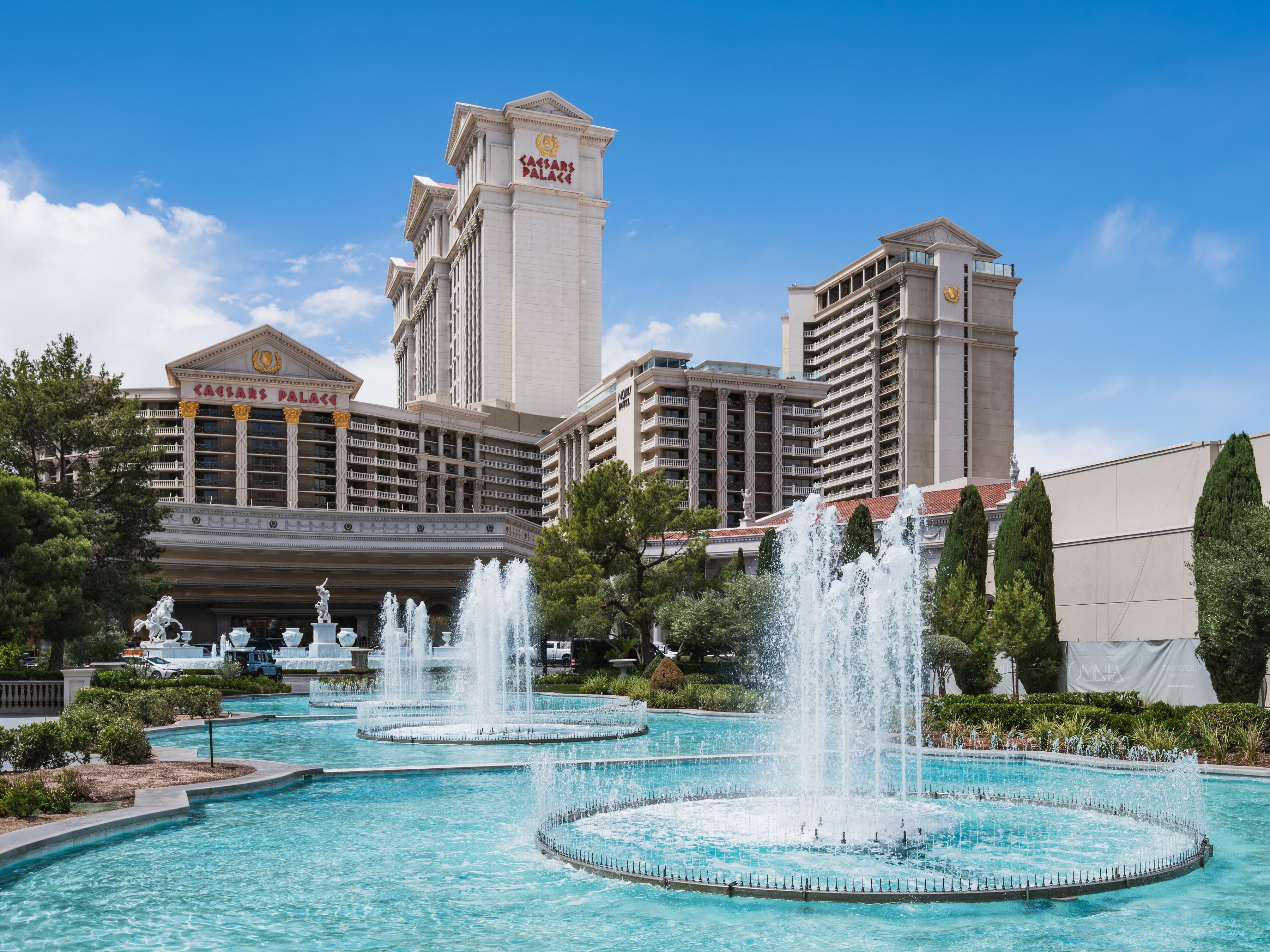 Caesars Palace towers behind the turquoise fountain pools on a clear day