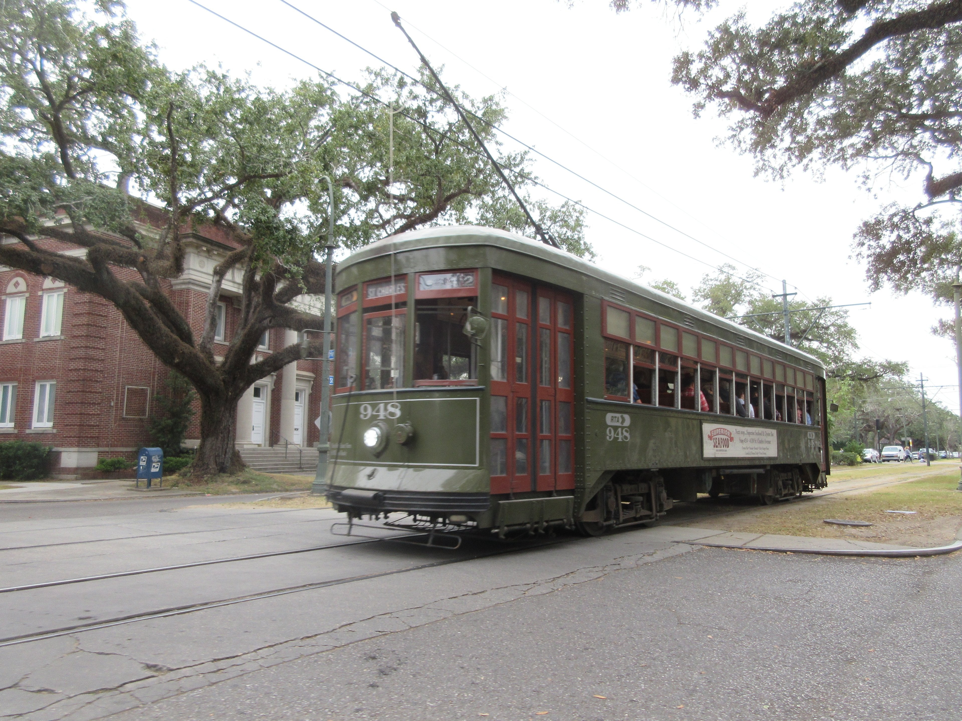 A green St. Charles streetcar under the oaks Uptown