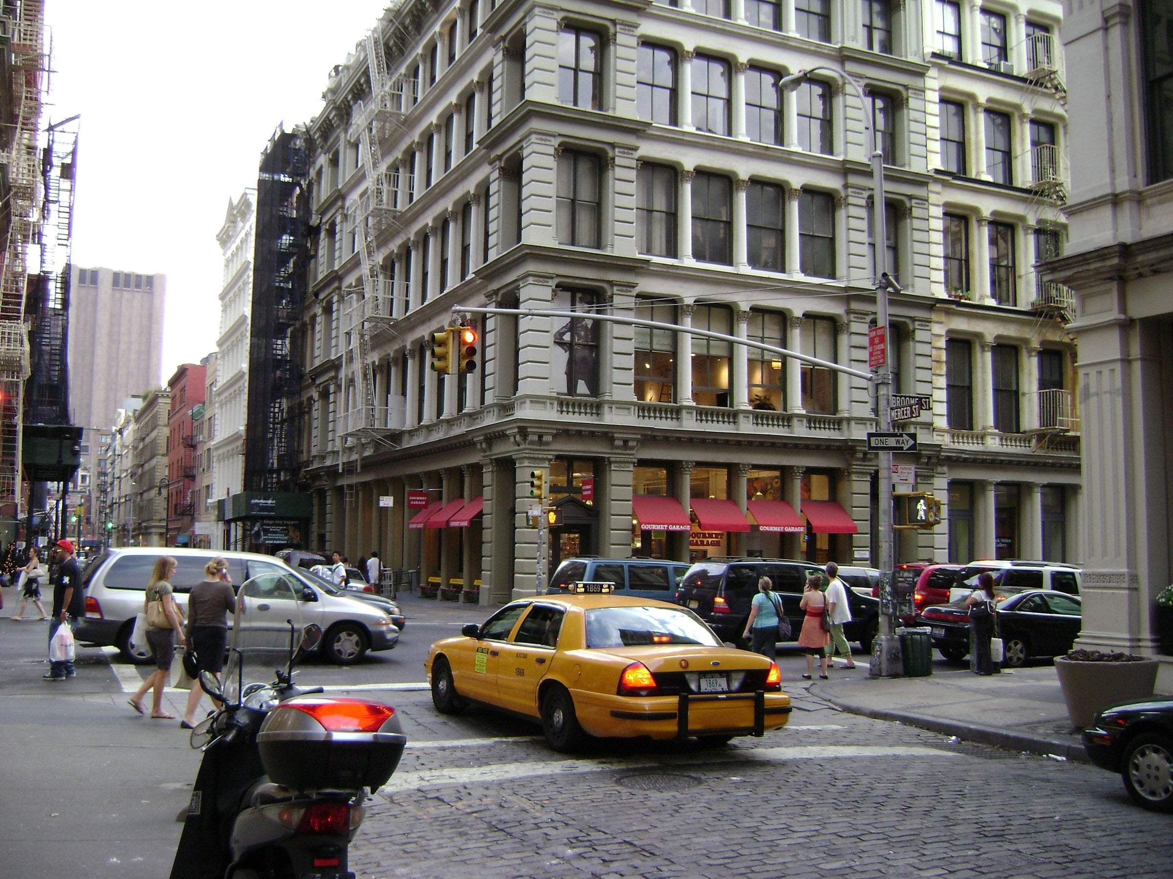Yellow cab passing cast-iron buildings at Mercer and Broome Streets in SoHo