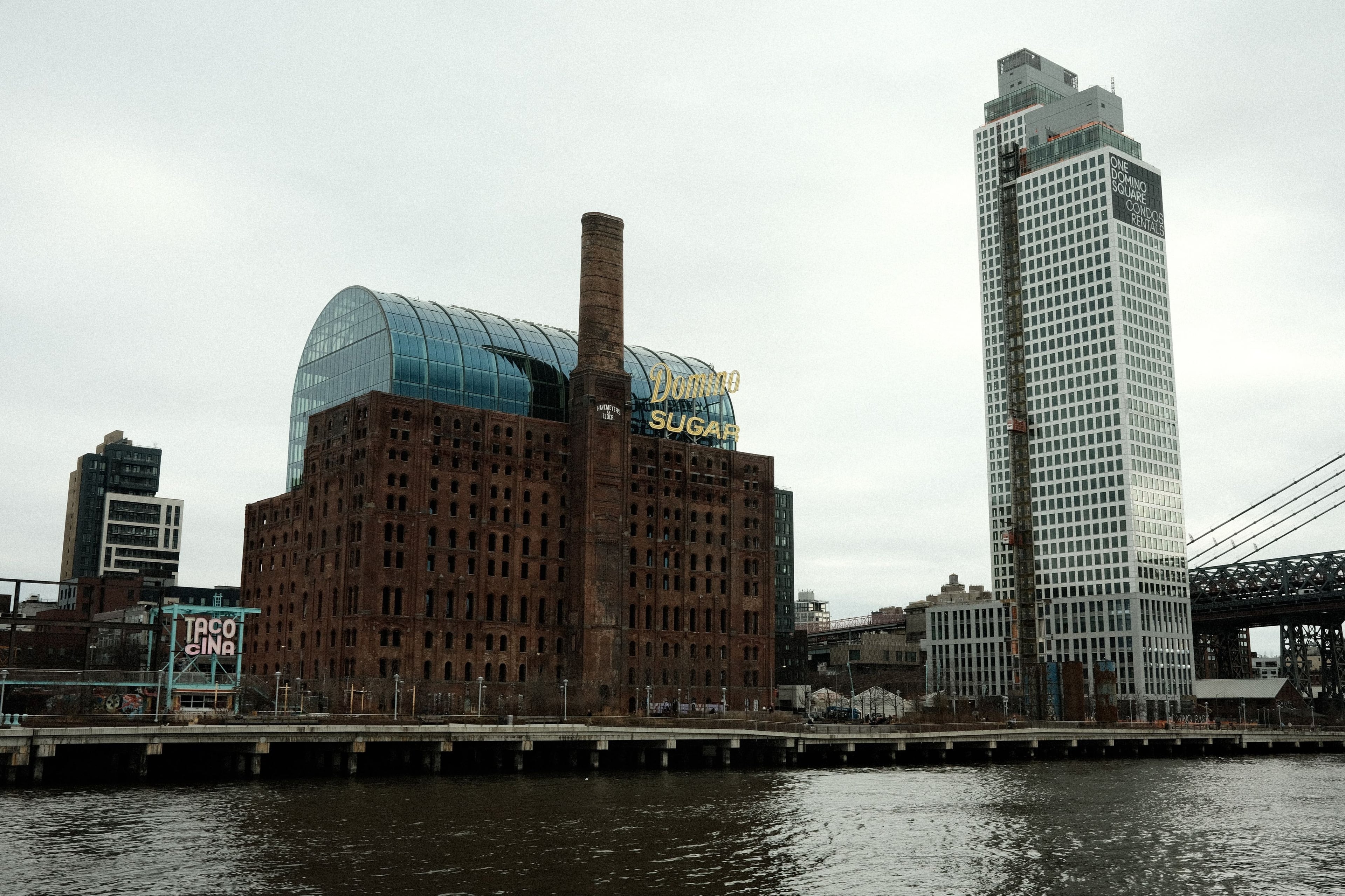 Domino Sugar Refinery and the Domino Park waterfront pier on the East River, Williamsburg Bridge at right